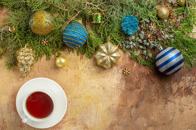 Top view fir branches xmas tree ornaments a cup of tea on beige background