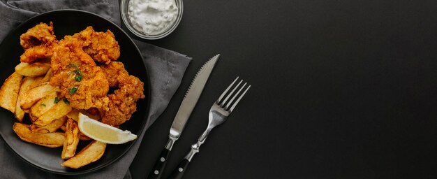 Top view of fish and chips on plate with lemon slice and copy space