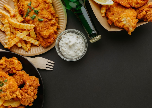 Top view of fish and chips on plates with cutlery and beer bottle