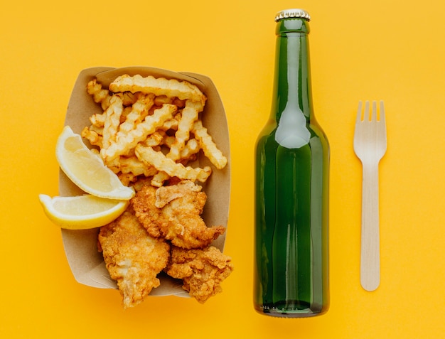 Foto gratuita vista dall'alto di fish and chips con bottiglia di birra e forchetta