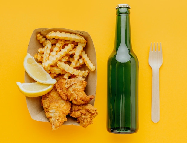 Top view of fish and chips with beer bottle and fork