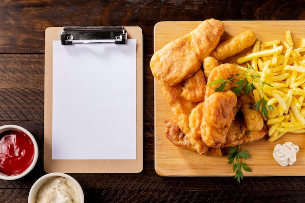 Top view of fish and chips with clipboard and ketchup