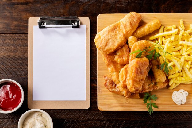 Top view of fish and chips with clipboard and ketchup