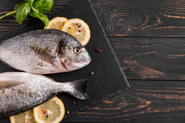 Top view fish and lemon on wooden background