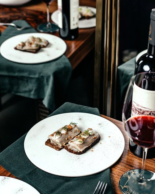 テーブルフードの食事レストランで赤ワインと一緒に白いプレート内のトップビュー魚の食事