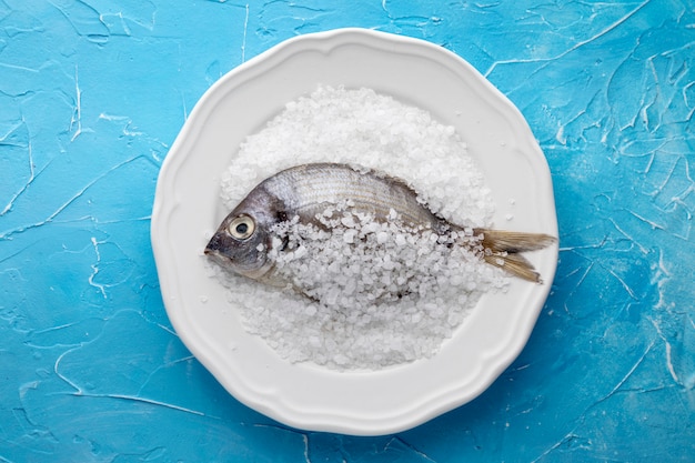 Вид сверху рыбы на тарелке с солью