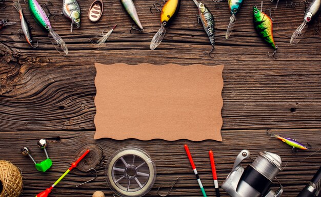 Top view of fishing equipment frame with multicolored bait and piece of paper