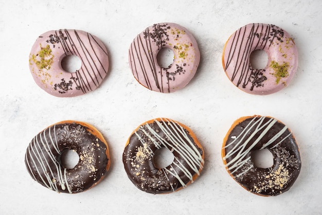 免费照片顶视图平躺的许多巧克力和白色表面上粉红色的甜甜圈。