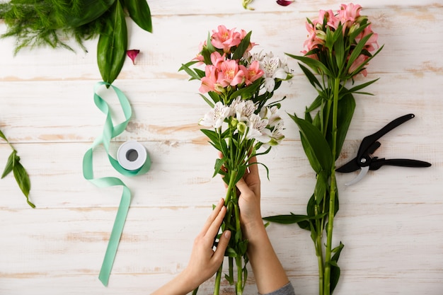 Top view florist hands making bouquet