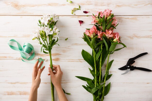 Top view florist hands making flower bouquet