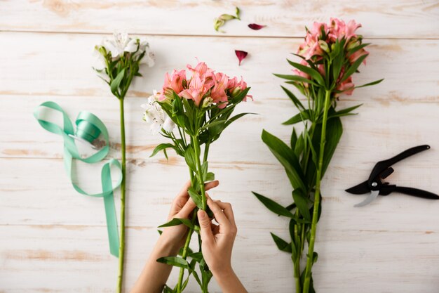 Top view florist hands making flower bouquet