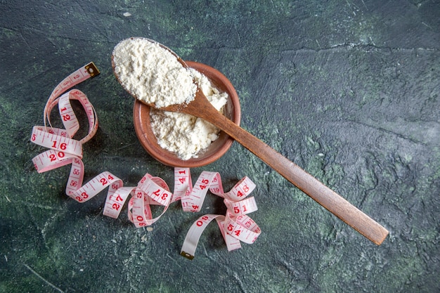 Top view flour with centimeters on dark desk