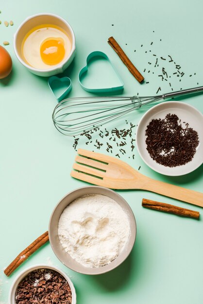 Top view flour with whisk and egg on the table