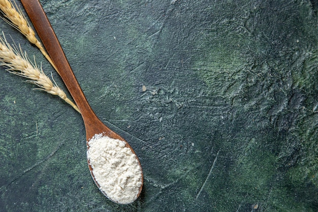 Top view flour on wooden spoon on dark desk