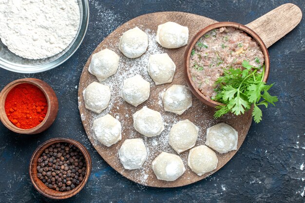 Top view of floured dough pieces with minced meat greens along with pepper on dark, dough food raw meat dinner pastry