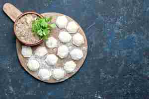 Free photo top view of floured dough pieces with minced meat greens on dark desk, dough food raw meat dinner pastry