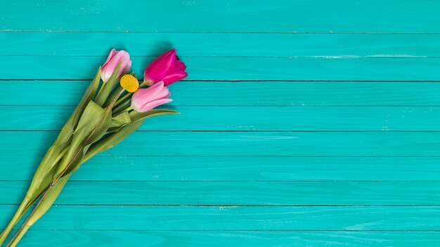 Top view of flowers against green wooden desk