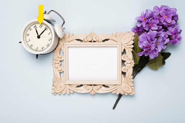 Top view flowers beside frame and clock