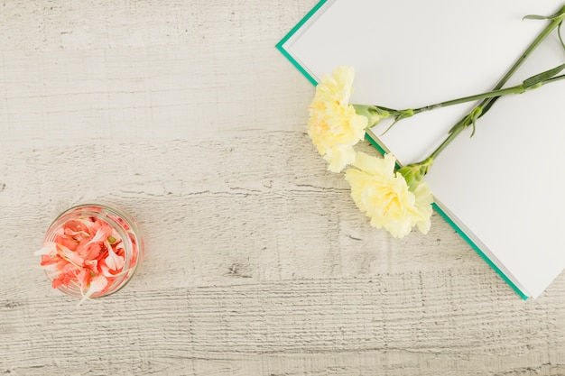 Top view flowers and book on wooden background