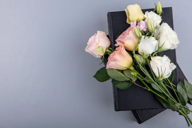 Top view of flowers on closed books on gray background with copy space