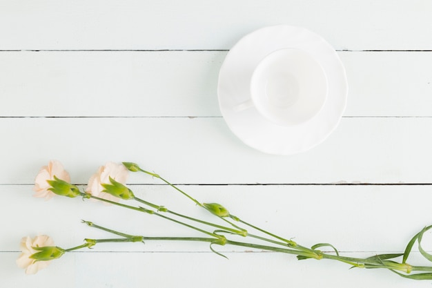 Free photo top view flowers and cup on wooden background