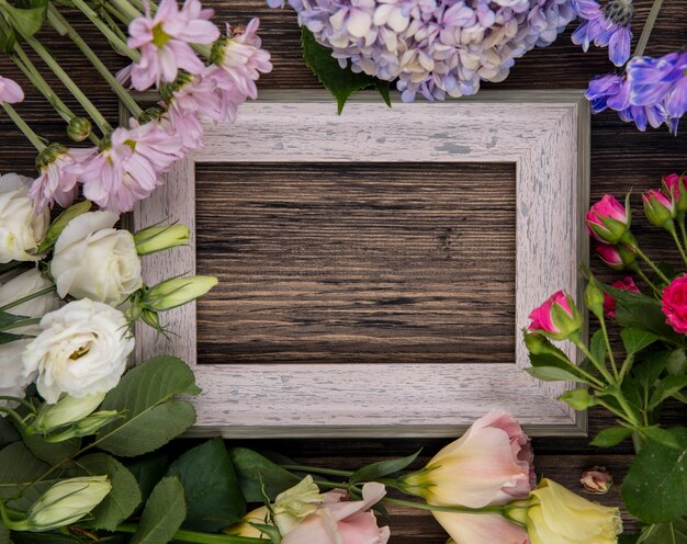 Free photo top view of flowers and frame on center on wooden background with copy space