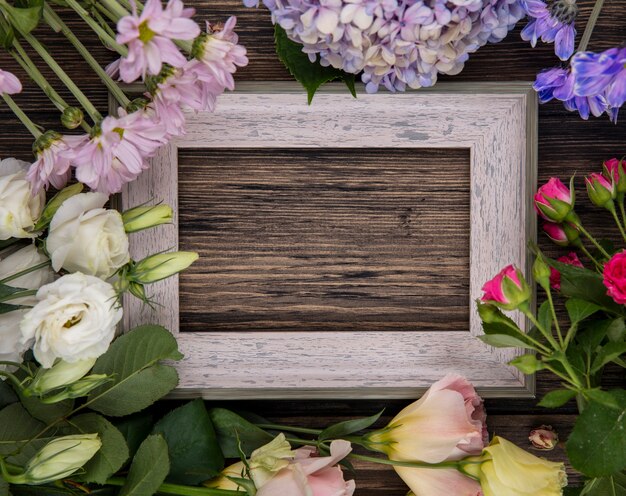 Вид сверху на цветы и рамка в центре на деревянном фоне с копией пространства