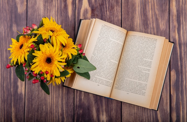 Top view of flowers and open book on wood