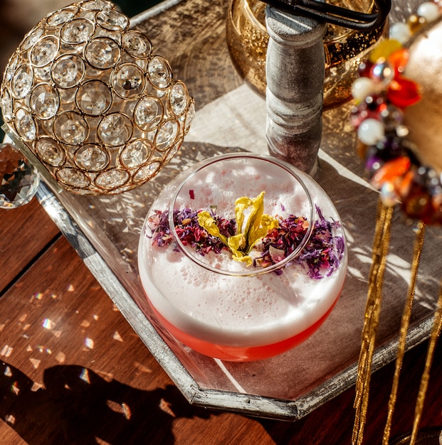 Top view of foamy cocktail glass garnished with dried flower petals
