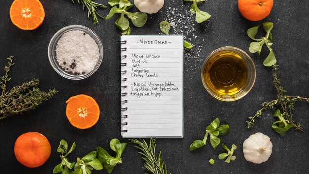 Top view of food ingredients with herbs and notebook