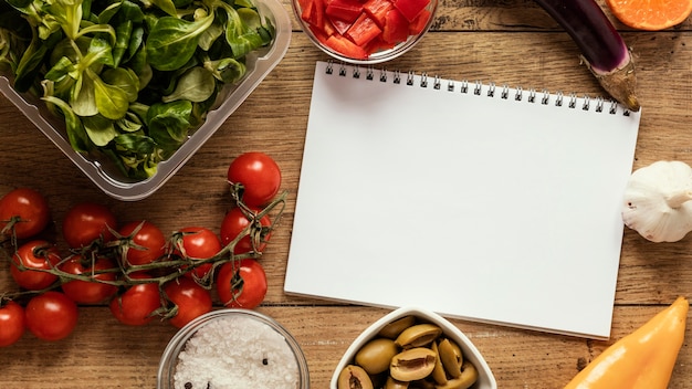 Top view of food ingredients with notebook and vegetables
