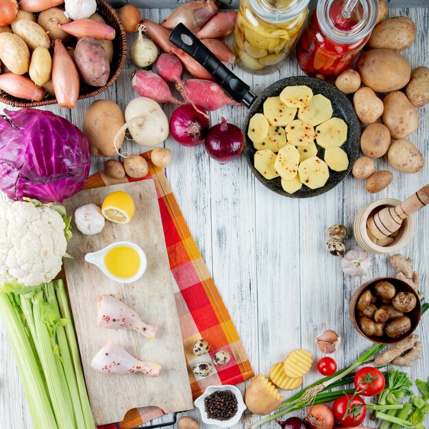 Top view of foods and vegetables as sour tomato chicken leg baked potato cabbage cauliflower celery and others on wooden background with copy space