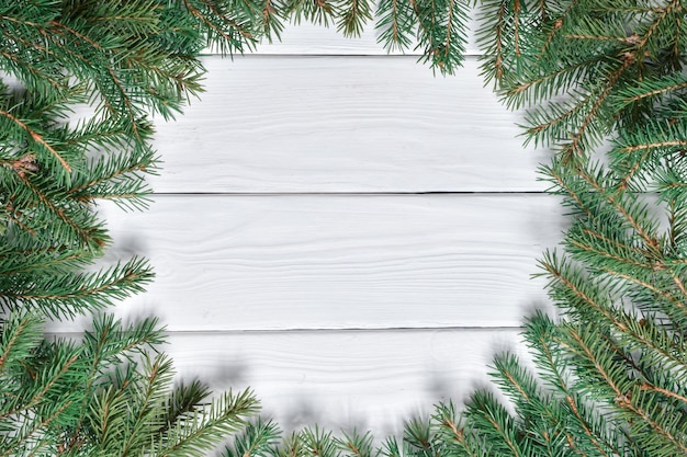 Top view of a frame of fir branches on a white wooden table.new year greeting card. a mock-up of a christmas greeting. copy space. flat lay.