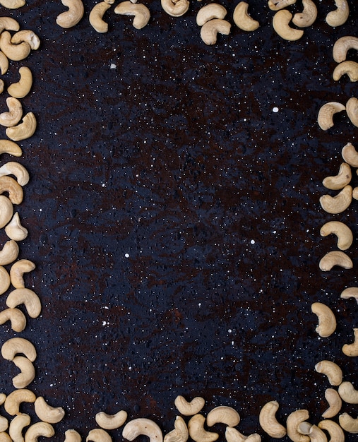 Top view of a frame made of cashew nuts on black background with copy space