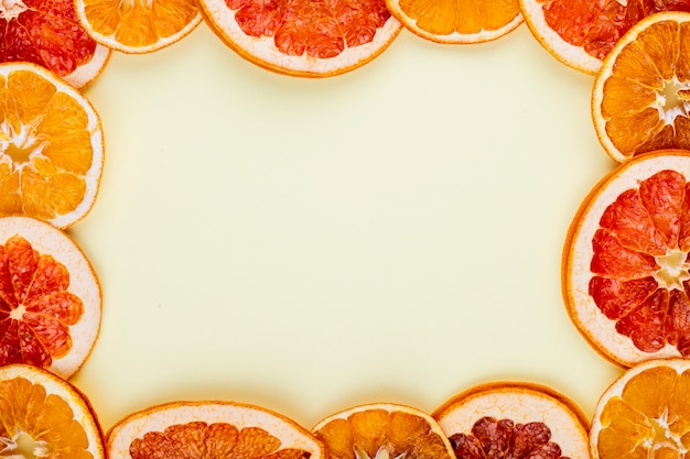 Вид сверху рама из сушеных ломтиков апельсина и грейпфрута, расположенных на белом фоне с копией пространства