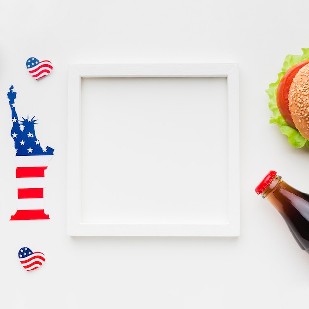 Top view of frame with burger and soda bottle next to statue of liberty