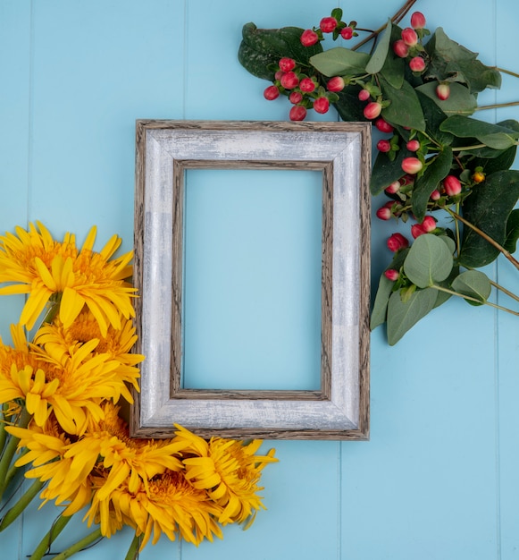 Free photo top view of frame with flowers around on blue with copy space