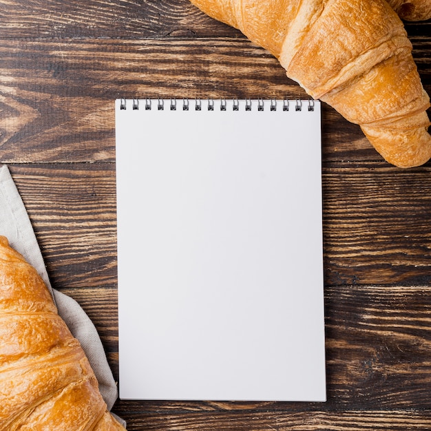 Free photo top view french croissants and empty copy space notepad