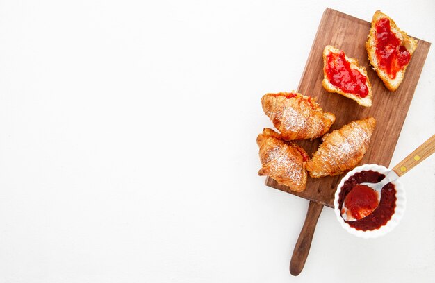 Top view french croissants and strawberry jam copy space