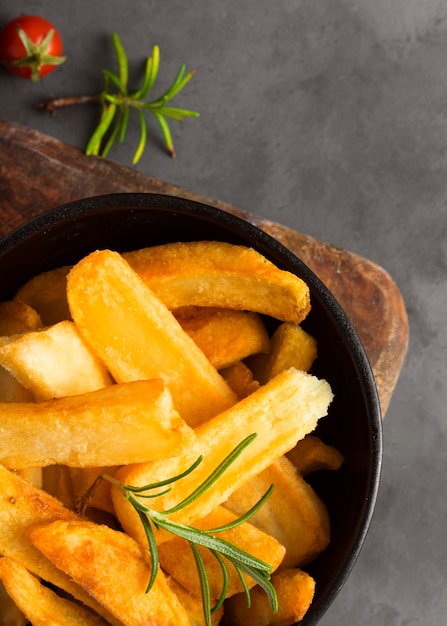 Top view of french fries in bowl with herbs