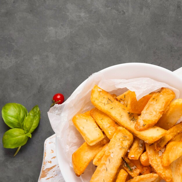 Top view of french fries on plate with herbs and copy space