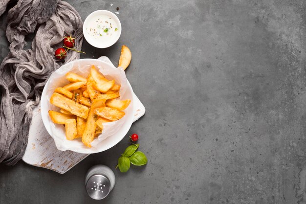 Top view of french fries on plate with salt shaker and copy space