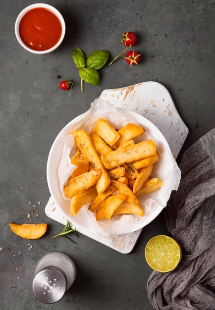 Top view of french fries on plate with tomatoes and ketchup