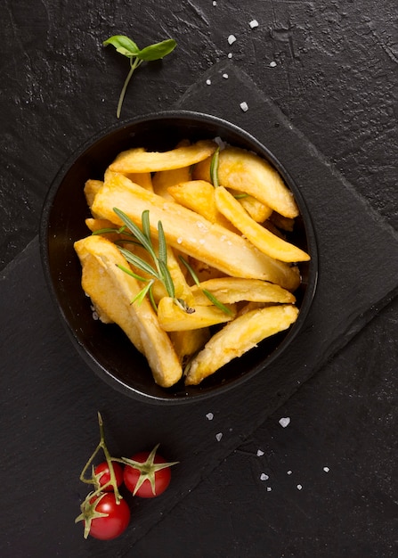 Top view of french fries on slate with herbs and salt