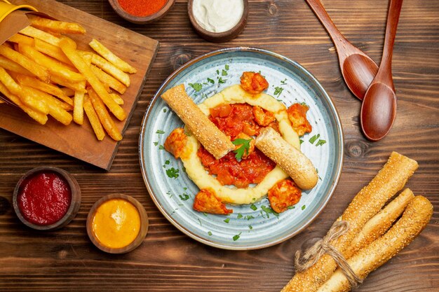 Top view of french fries with chicken slices on brown table