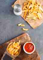 Free photo top view of french fries with ketchup and salt shaker