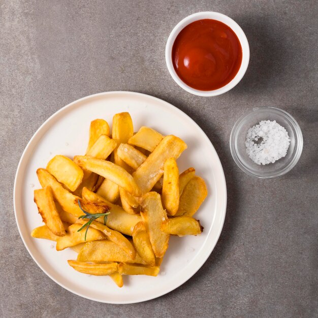 Top view of french fries with ketchup and salt