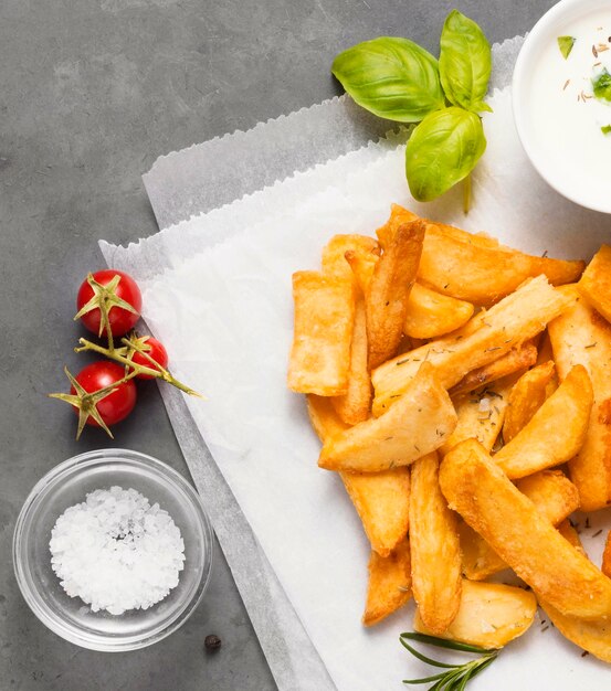 Top view of french fries with salt and bowl of sauce