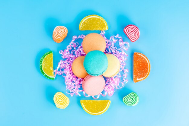 A top view french macarons along with colorful marmalades on the blue background confiture confectionery sugar cake