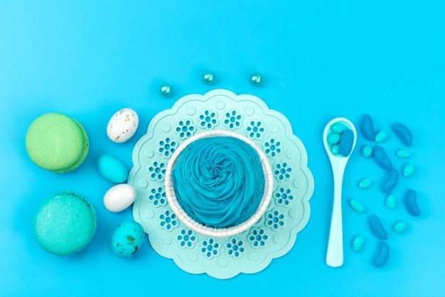 Вид сверху французские макароны с безе и ложками на синем сладком цвете торта